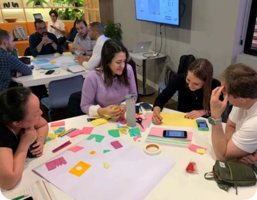 Colaboradores da Neodent em oficina prática, com post-its e papéis coloridos sobre a mesa