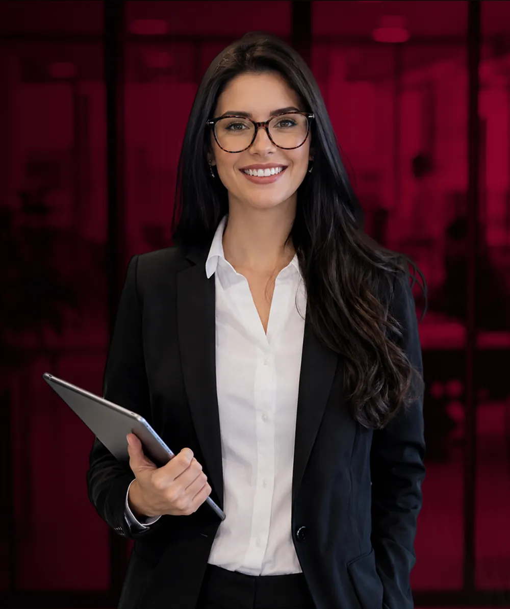 Executiva sorridente, de óculos e blazer, segurando um tablet em um escritório iluminado em vermelho