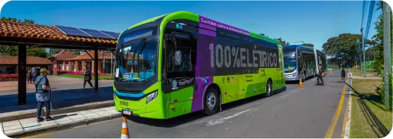 Ônibus elétrico verde e roxo em um terminal de Curitiba
