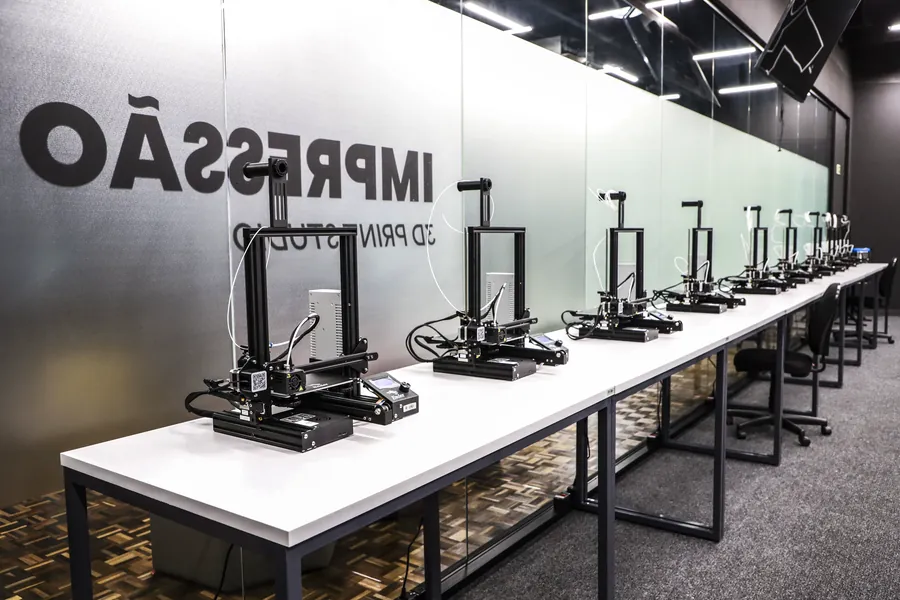 Fab Lab com impressoras 3D alinhadas em uma bancada