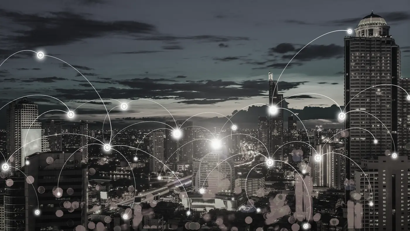 Cidade ao anoitecer com pontos de luz conectados por linhas, representando redes elétricas inteligentes